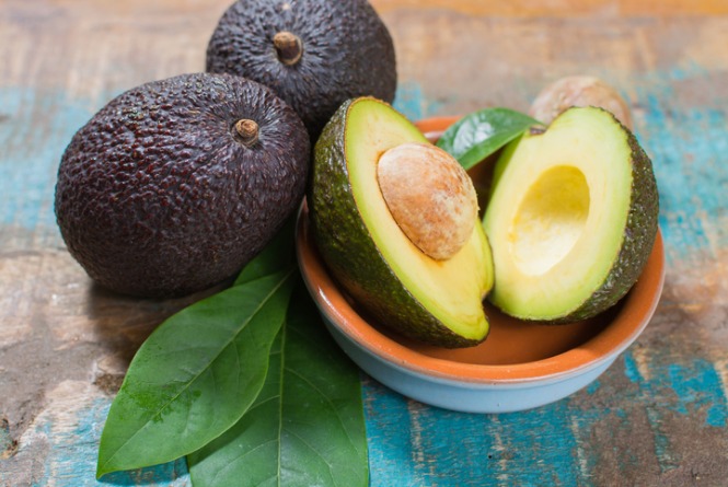 ripe-fresh-avocado-with-leaves-on-blue-wooden-table-picture-id848717218